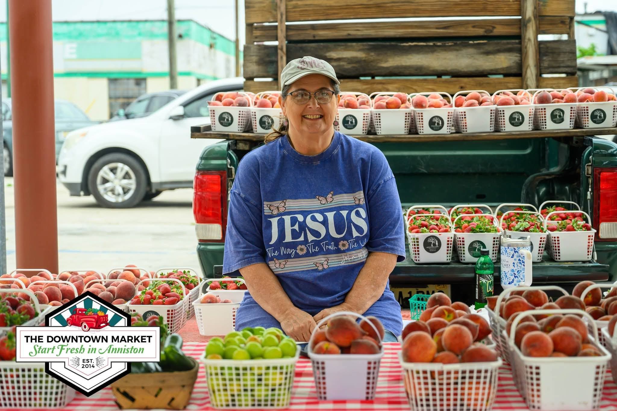 Market vendor displaying fresh peaches and produce
